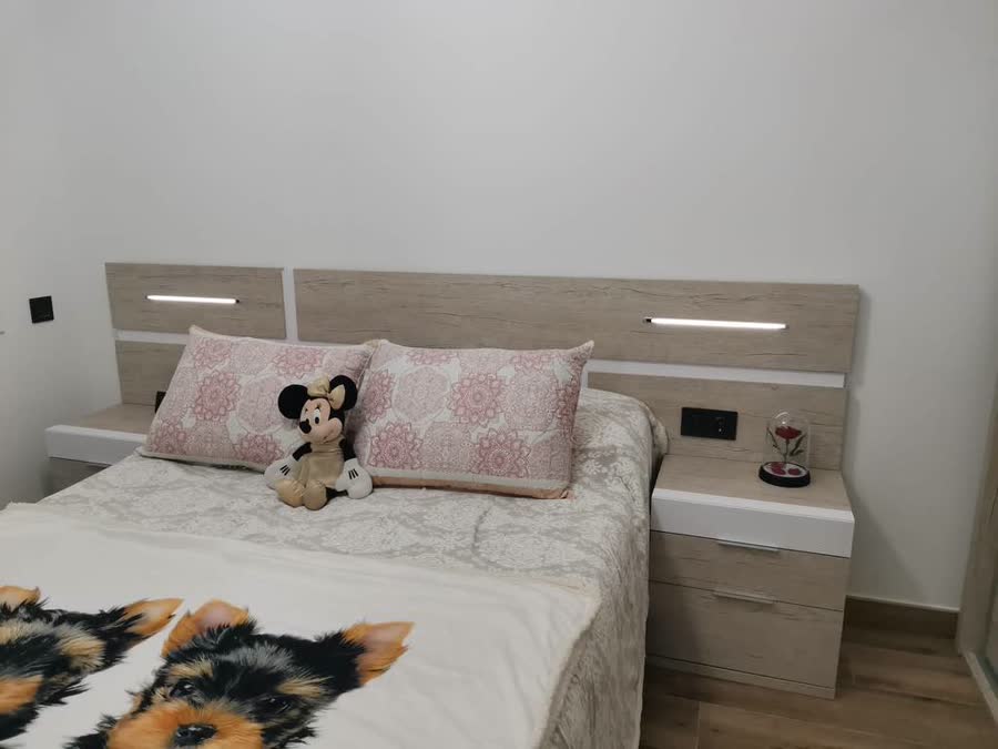 Dormitorio con cama doble y mesitas de noche en madera clara