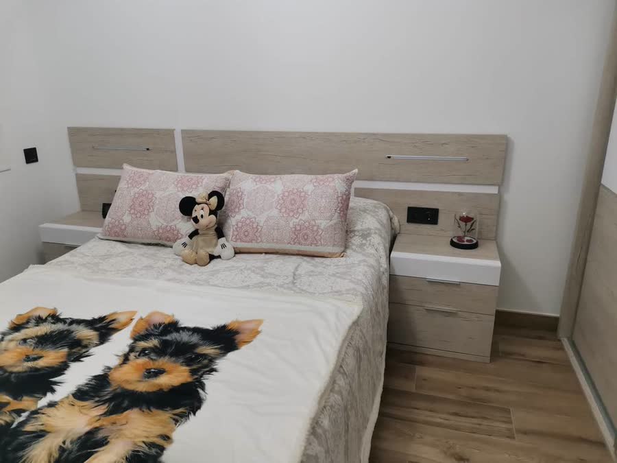 Dormitorio con cama grande y cabecero largo en madera clara