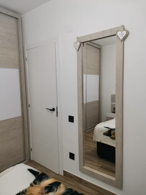 Dormitorio con espejo grande y armario en madera clara