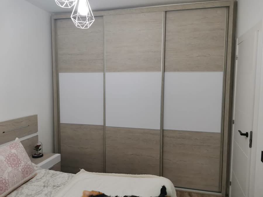 Dormitorio con armario de puertas correderas y cama en madera clara