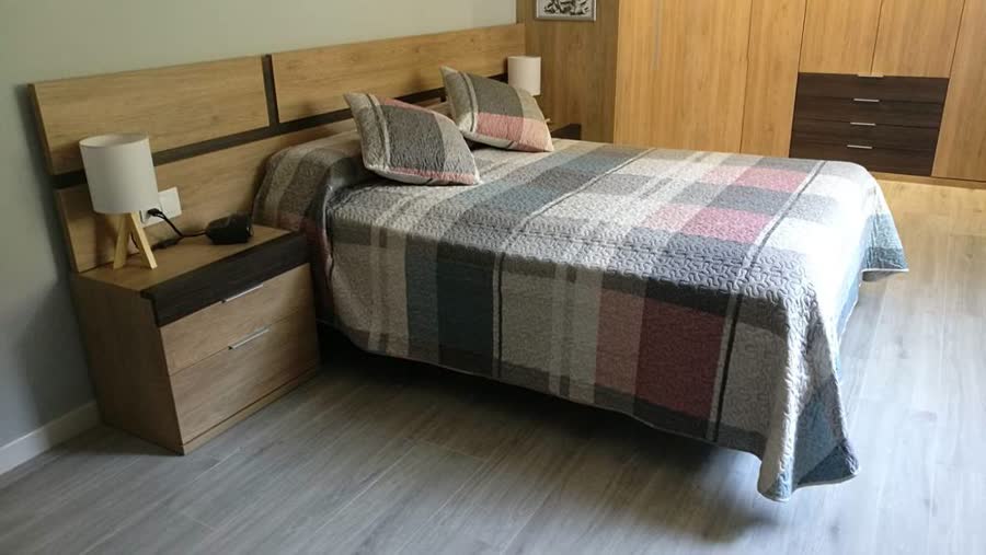 Dormitorio con cama y mueble auxiliar en madera clara
