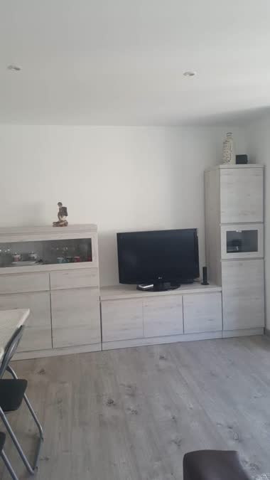 Comedor con televisor y muebles bajos en blanco
